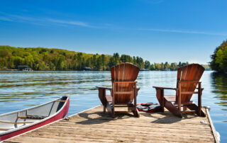 Two Muskoka chairs on a wooden dock in Ontario Canada